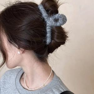 Primo piano di una molletta per capelli in peluche grigio indossata per un look elegante autunnale