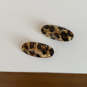 Detail of two oval leopard print hair clips with a glossy finish for vintage styling