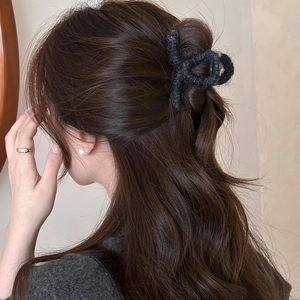 Dettaglio della molletta per capelli in maglia grigio scuro su acconciatura mossa