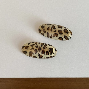 Close-up of two oval leopard print hair clips with glossy finish on a clean background