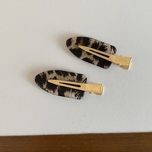 Macro detail of leopard print acetate hair clips with gold metal flat duckbill closure
