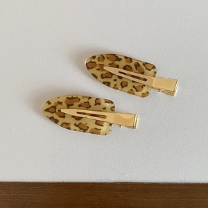 Detailed view of the pair of leopard print oval hair clips with golden metal duckbill base