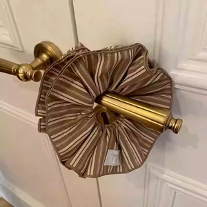 Macro shot of oversized coffee striped hair scrunchy with wavy ruffle on a door handle