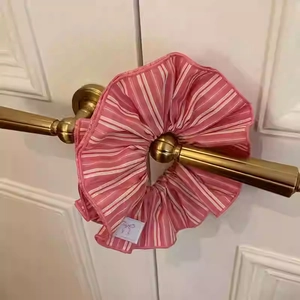 Detail of pink and white striped scrunchie with a logo label on a golden door handle