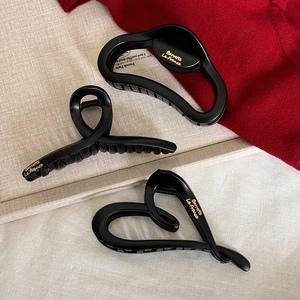Three minimalist black claw clips in different shapes with elegant gold lettering