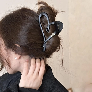 Detail view of a matte black heart-shaped hair claw clip on brunette hair