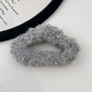 Detailed close-up of a large grey plush hair scrunchie with fluffy faux fur texture