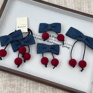 Élastiques à cheveux nœud en jean et cerises rouges sur un plateau blanc