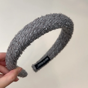 Detail of grey knitted headband with silver sequins and a handmade woven label