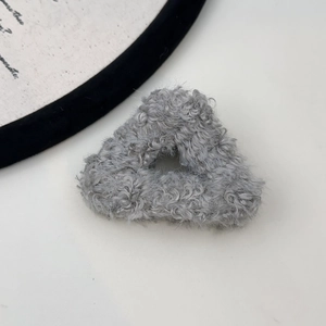 Close-up of a triangular plush hair claw in light grey wool-like fabric texture