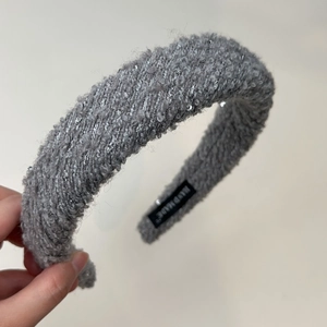 Close-up of grey bouclé headband texture with shimmering silver sequins and handmade label