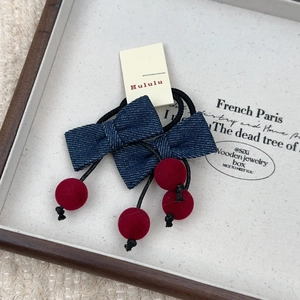 Détail d'élastiques à cheveux avec nœud en denim et cerises en velours rouge foncé