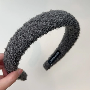 Close-up of thick grey textured knit headband with a Hand Made label showing fabric detail
