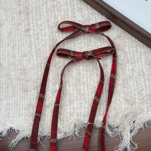 Close-up of red plaid bow hair clips with long ribbons in vintage tweed fabric