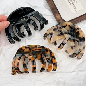 Three-piece set of acetate hair claws in black and tortoiseshell finishes held by hand