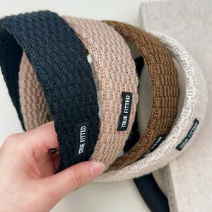 Solid color knitted wide headband for women featuring a thick textured weave and brand label