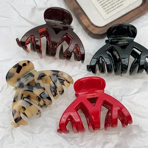 Thick acetate hair claws in four colors with gold logo detail and glossy finish