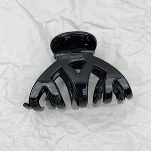 Detailed macro view of black acetate hair claw clip featuring golden France Handmade text