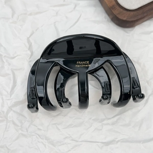 Detail of glossy black acetate hair claw clip featuring gold France Handmade logo