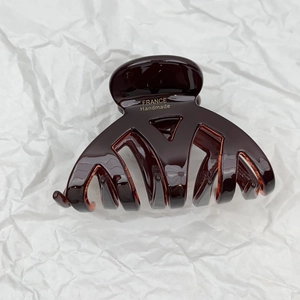 Macro detail of dark brown tortoiseshell claw clip with gold France Handmade logo