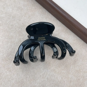 Détail d'une pince à cheveux noire brillante avec lettrage doré France Handmade