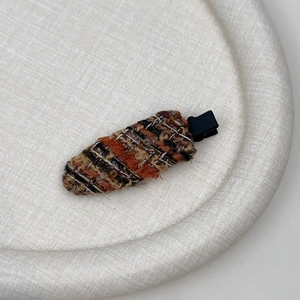 Detailansicht der ovalen Tweed-Haarspange mit vintage braun-orangefarbenem Webmuster