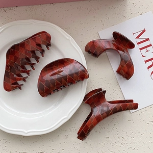 Elegant red plaid hair claw clips set in British style on white porcelain display