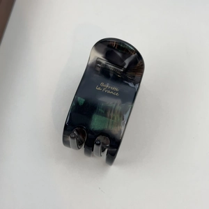 Detail der Haarklammer aus grauem Acetat mit grüner Marmorierung und Goldlogo