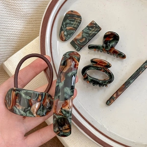 Handmade acetate hair accessories set with tortoiseshell pattern on white porcelain tray