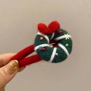 Détail de pince à cheveux couronne de Noël en feutre vert avec poignée en peluche rouge