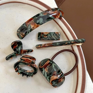 Flat lay of vintage marble texture acetate hair clips and scrunchie set on white ceramic
