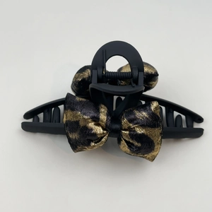 Detail view of stylish matte black hair claw with elegant leopard print fabric bows