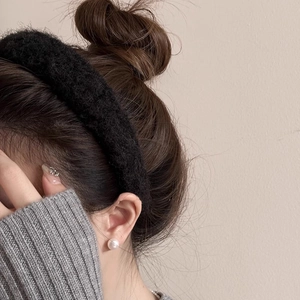 Détail d'un serre-tête en peluche noire porté par un mannequin avec des boucles d'oreilles
