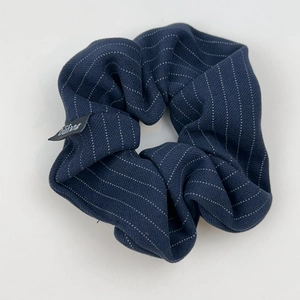 Gros plan sur un chouchou bleu marine avec motif à rayures blanches et étiquette logo
