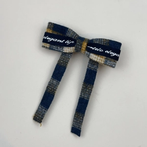 Detail of blue and yellow plaid bow hair clip with elegant life printed ribbon