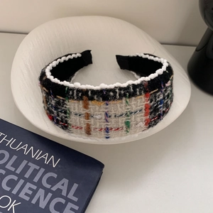Detailed close-up of a wide vintage tweed headband with colorful weave and lace edge