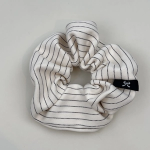 Détail d'un chouchou rayé montrant la texture du tissu et l'étiquette logo
