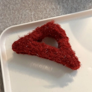 Macro shot of red plush triangular hair claw clip with shimmering silver tinsel detail