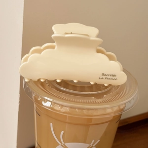 Close-up of cream acetate hair claw clip with La France text on a minimalist coffee cup