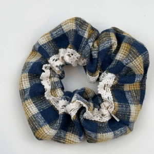 Detail of blue and yellow plaid scrunchie with delicate white lace trim and cotton texture