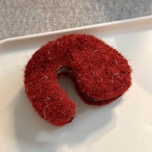 Detail of red hollow geometric hair claw with fuzzy texture and subtle silver silk accents