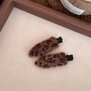 Close-up of leopard print plush hair clips with soft faux fur texture and black beak clips
