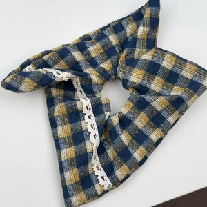 Detail of blue and yellow plaid fabric hair clip with delicate white lace edge