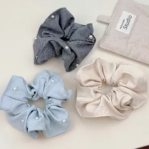 Floral jacquard fabric scrunchies with white pearl accents in grey, blue, and beige