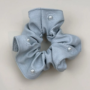 Detailed view of light blue scrunchie with soft fabric texture and pearl embellishments