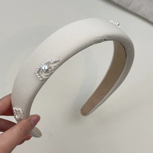 Detail of cream fabric headband with elegant pearl crescent floral pattern design