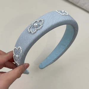 Detail of light blue padded sponge headband with hand-sewn pearl flower patterns