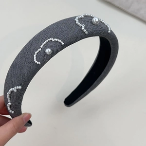 Detail of grey fabric headband featuring elegant white pearl wave pattern embellishments