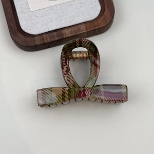 Detailed top view of a classic red and green plaid shark hair clip on a white surface