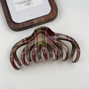 Close-up of a high-gloss tartan hair claw clip with red and green Christmas style pattern